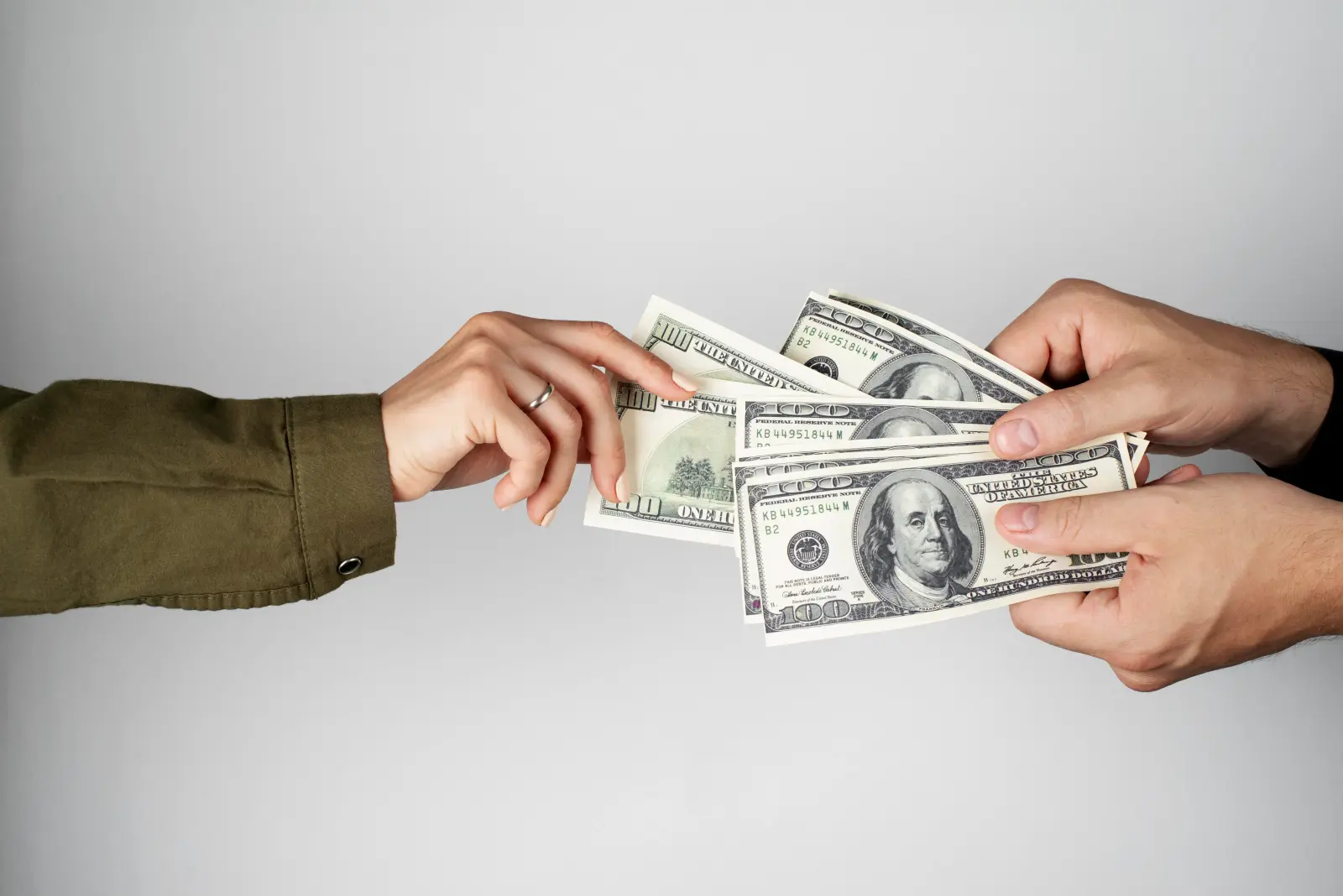 Dos personas intercambiando billetes de cien dólares