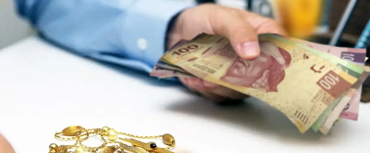 Un cliente recibe billetes sobre el mostrador, junto a alhajas de oro Un cliente recibe billetes sobre el mostrador, junto a alhajas de oro
